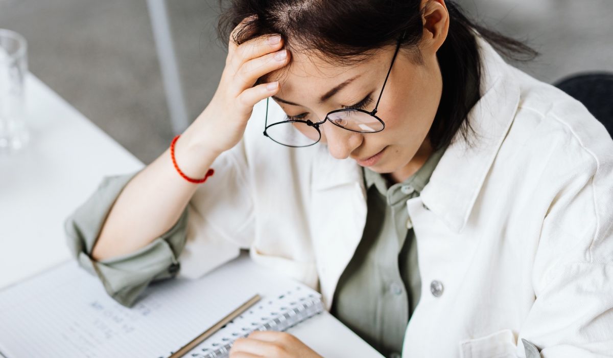 woman staring down at work on laptop with her hand on her head looking stressed